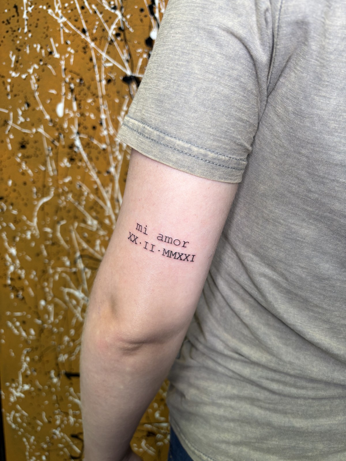 Fine line lettering tattoo: mi amor, with a date in roman numerals